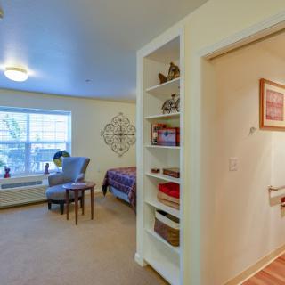 A cozy bedroom with a comfortable seating area and well-organized shelves.