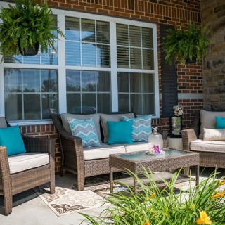 A cozy patio with wicker furniture and colorful cushions, complemented by hanging plants.
