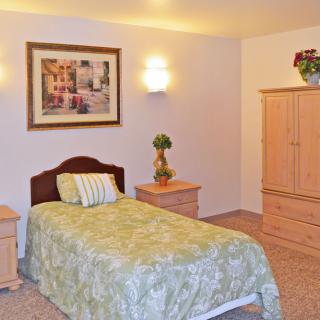 A cozy bedroom with a single bed, bedside tables, and a wardrobe.