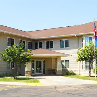 A modern building featuring an entrance with landscaped areas and flags displayed.