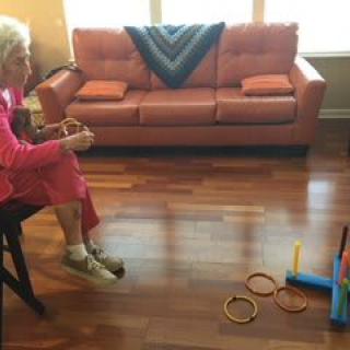 An elderly person playing a ring toss game in the living room.