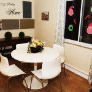 A cozy dining room with a modern round table and white chairs, featuring elegant wall art and window decorations.