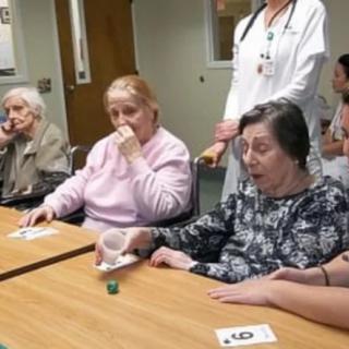 Elderly residents participating in a group activity at a nursing home with healthcare staff present.