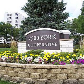 Entrance sign of the 7500 York Cooperative, surrounded by vibrant flowers and greenery.