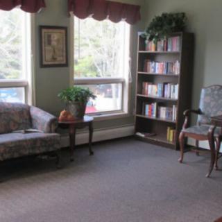 A cozy living room with a sofa, bookshelf, and large windows letting in natural light.