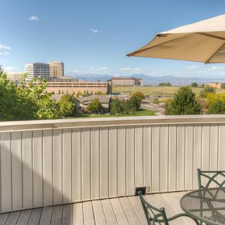 A deck with outdoor furniture and an umbrella overlooking a cityscape with mountains in the background.