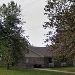 A peaceful suburban home surrounded by trees and a green lawn.