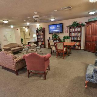 A cozy living room with sofas, chairs, bookshelves, and a television.