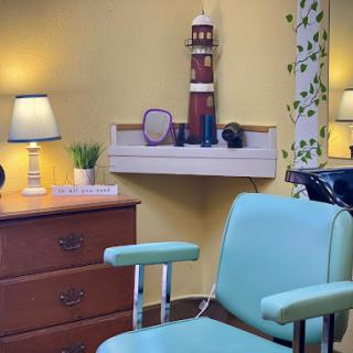 A cozy and inviting interior of a salon or dental office featuring a vintage chair, soft lighting, and decorative elements.