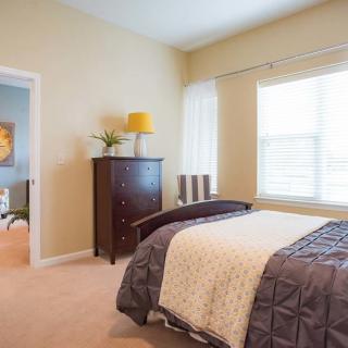 A cozy bedroom with a neatly made bed, a window letting in natural light, and stylish decor.