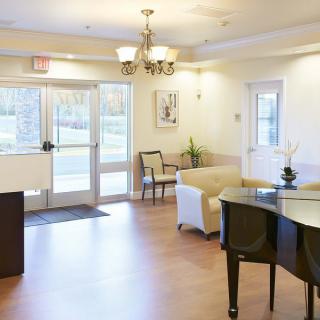 A welcoming lobby area featuring a piano, comfortable seating, and a chandelier.