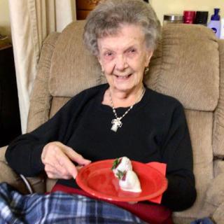 A cheerful senior woman enjoying a treat while seated comfortably in her living room.