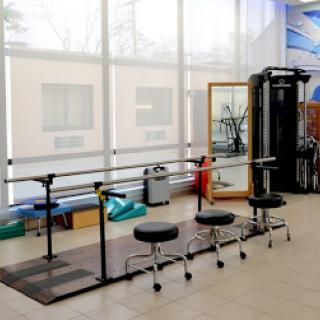 A well-equipped studio featuring a ballet barre, stools, and mirrors for fitness and rehabilitation exercises.
