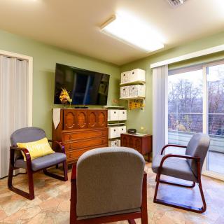 A modern living room with comfortable seating, a large TV, and shelves near a window providing natural light.
