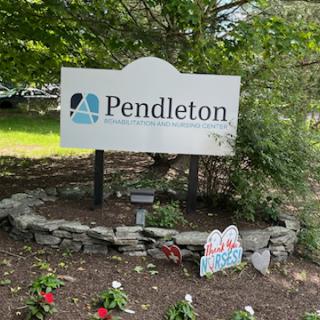 A welcoming sign for Pendleton, surrounded by flowers and greenery.