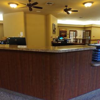 A spacious reception desk with overhead ceiling fans in a lobby area.