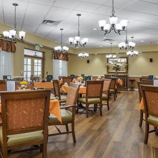 A spacious dining room with elegant chandeliers and neatly arranged tables and chairs.