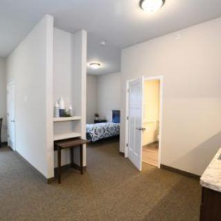 A minimalist bedroom with a bed, furniture, and an open doorway.