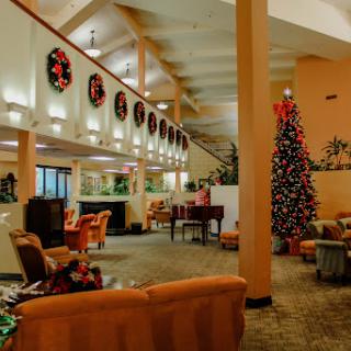 A cozy lobby decorated for the holiday season featuring a Christmas tree and festive wreaths.