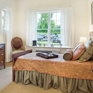A cozy bedroom with elegant decor, featuring a bed near a large window that offers natural light.