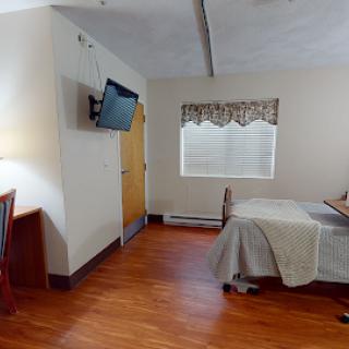 A cozy hotel room featuring a bed, television, and simple furnishings.