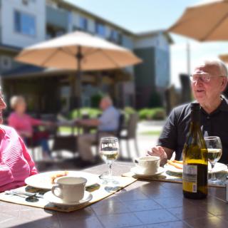 Two people enjoying a meal at an outdoor restaurant on a sunny day.