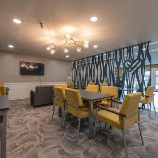 A stylish dining area with yellow chairs and a modern chandelier, featuring a decorative partition.