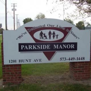 A sign for Parkside Manor located on a brick base, displaying contact details and the slogan 'We've Completed Our Family Circle'.