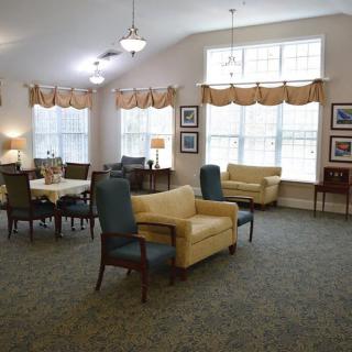 A cozy living room with sofas, chairs, and a table arranged near large windows.