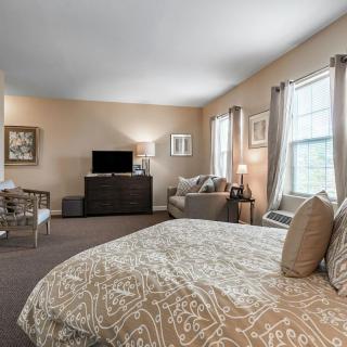 Spacious bedroom with cozy decor, featuring a bed, sofa, and a TV.