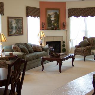 A cozy living room with elegant furniture, including a sofa and armchairs surrounding a fireplace.