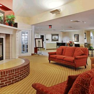A cozy hotel lobby featuring a brick fireplace and red sofas.
