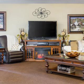 A cozy living room with a television, sofa, armchair, and decorative elements.