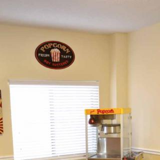 A cozy kitchen corner featuring a popcorn machine and a vintage-style popcorn sign on the wall.