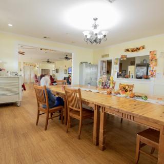 A cozy dining area with a large wooden table and chairs in a well-lit kitchen setting.