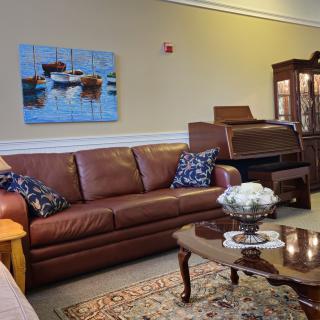 A cozy living room with a leather sofa, a wooden coffee table, and wall art.