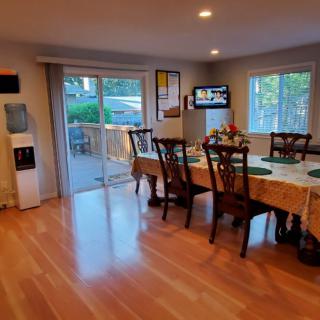 A spacious dining room with a table set for meals, featuring hardwood floors and a sliding glass door leading to an outdoor area.
