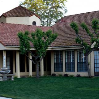 A suburban house with a tiled roof, large windows, and a neatly maintained lawn.