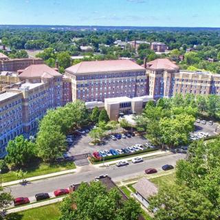 Aerial view of a large building surrounded by trees and parking areas.