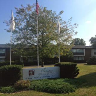 An exterior view of a building featuring multiple flags and well-maintained landscaping.
