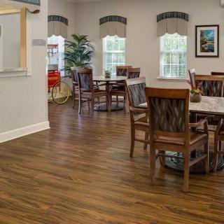 A well-lit dining area with wooden floors, tables, and chairs.