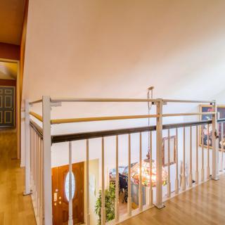 A modern loft interior with a railing and chandelier overlooking stairs.