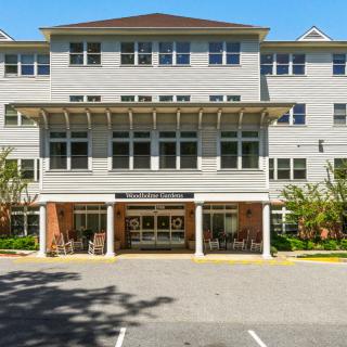 A modern multi-story residential building with a welcoming entrance and adjacent parking area.