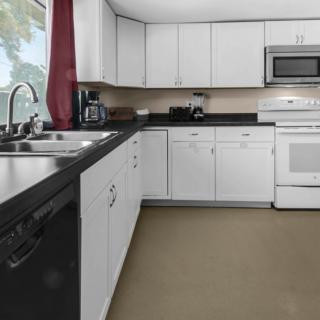 A modern kitchen with white cabinets and a black countertop.