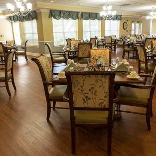 A elegantly decorated dining room with multiple tables and chairs, set for a meal.