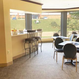 A cozy indoor bar and seating area with natural light streaming through large windows.