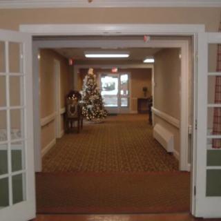 A view of a hallway with open double doors and a decorated tree in the distance.