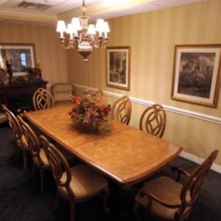 A well-decorated dining room with a large wooden table, surrounded by chairs and illuminated by a chandelier.