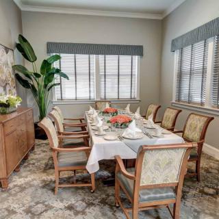 A beautifully set dining table in an elegant dining room with large windows.