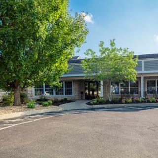 A modern office building surrounded by lush greenery on a sunny day.